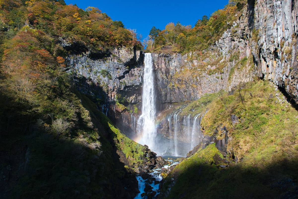 Kegon-fossen i Nikko styrter i ett fall ned en mørk klippevegg, omkranset av høstfargede lier