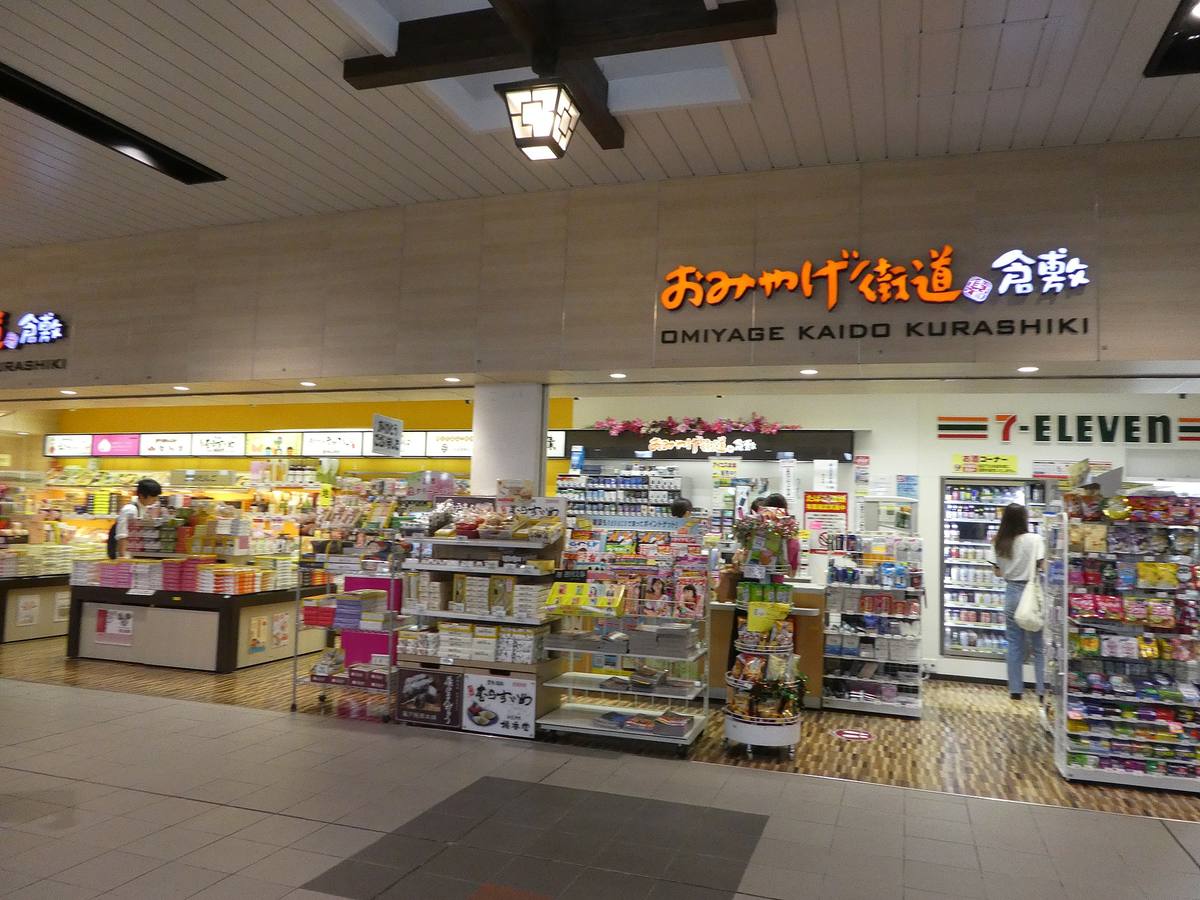 Souvenirbutikk med skiltet Omiyage Kaido, fylt av hyller med innpakkede kakeesker i pastellfarger