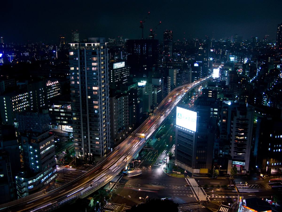 Utsikt fra et hotellrom over Tokyo om kvelden, med opplyste kontorbygg og lysstriper fra trafikken nedenfor