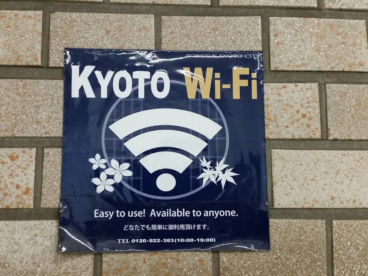 Mørkeblått klistremerke på en flislagt vegg med et stort wifi-symbol og teksten om at det kommunale trådløse nettet er gratis og åpent for alle