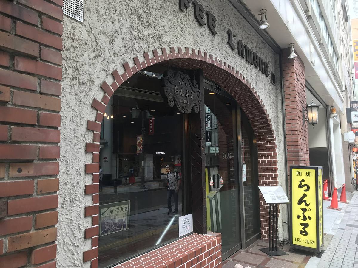 Inngangen til en gammeldags japansk kaffebar i murbygg, med buet portal og skilt med tegnet for kaffe
