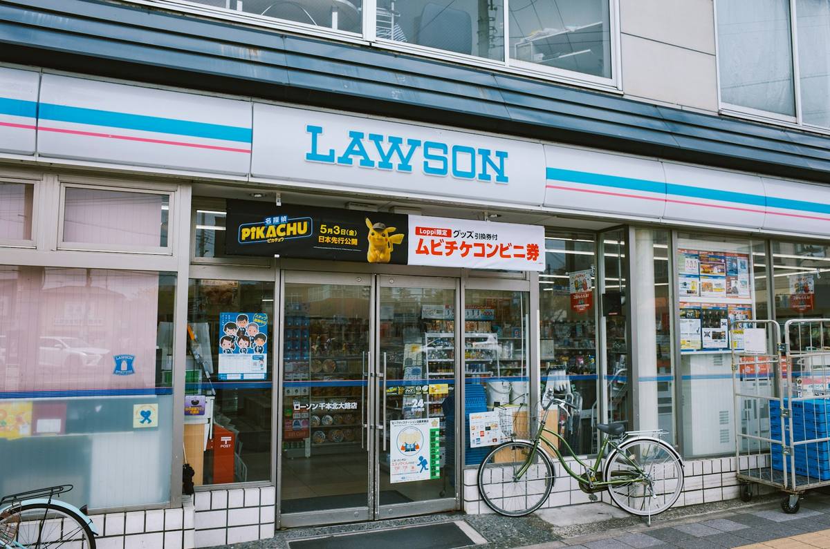 Fasaden på en Lawson-nærbutikk med blå skiltstripe, glassdører og varehyller synlige innenfor