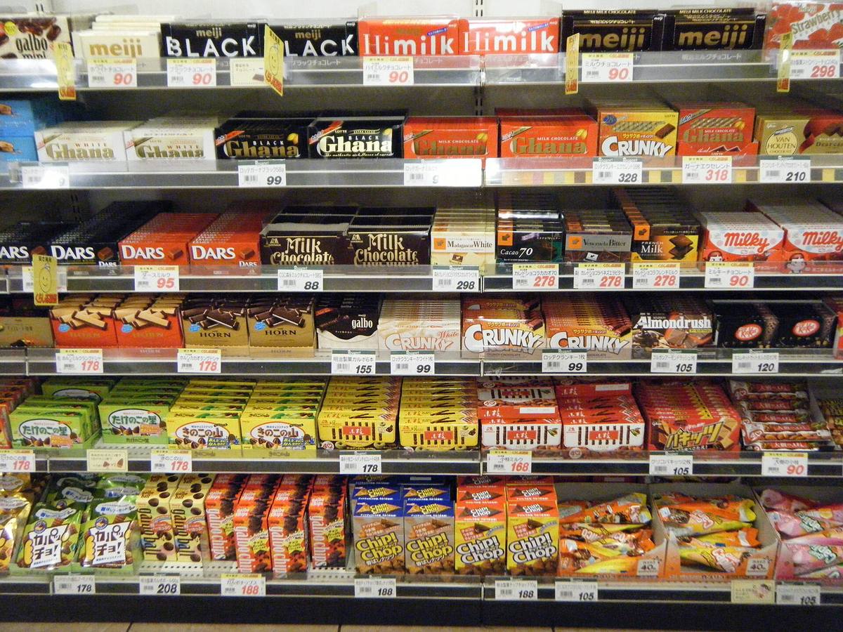 Butikkhylle i en japansk dagligvarebutikk full av sjokolade i esker med japansk tekst og prislapper