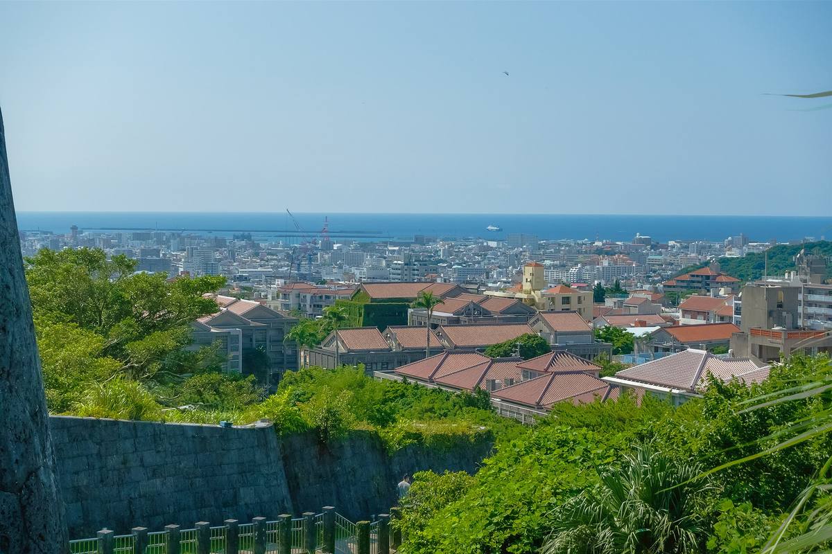 Utsikt over Naha fra Shuri-borgens park, med rødteglede tak i forgrunnen og havet bakerst