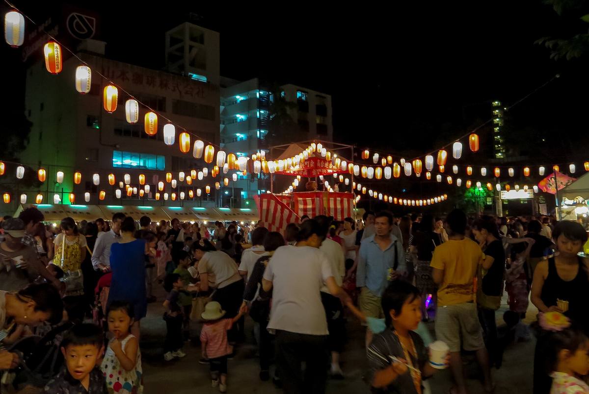 Bon odori om kvelden med rekker av opplyste papirlykter spent over plassen og et rødt tårn i midten