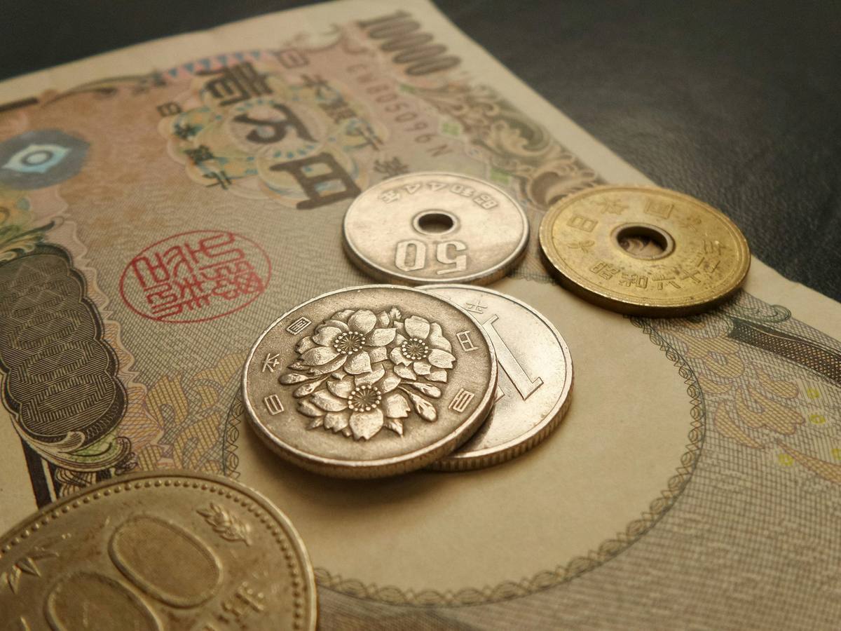 Seddel på 10 000 yen med et knippe japanske mynter oppå, blant dem femyen- og femtiyenmynten med hull i midten