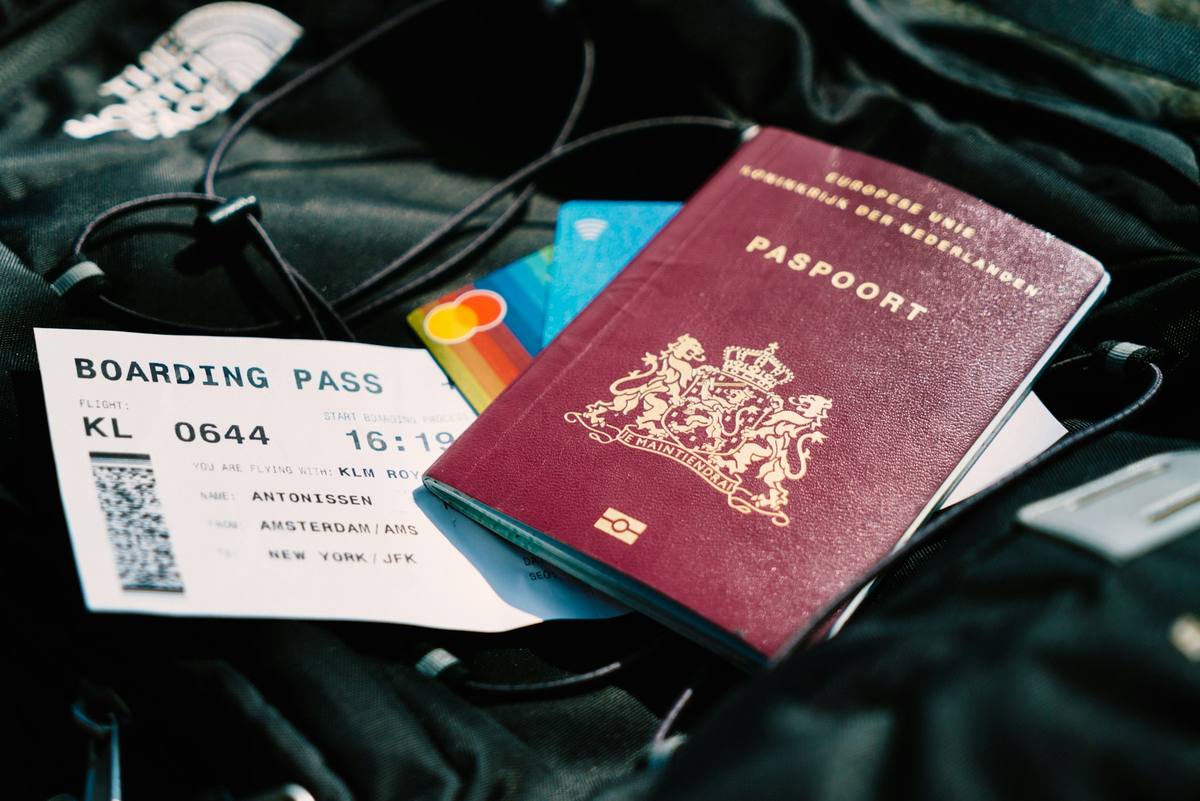 Pass, boardingkort og et par bankkort ligger oppå en svart ryggsekk