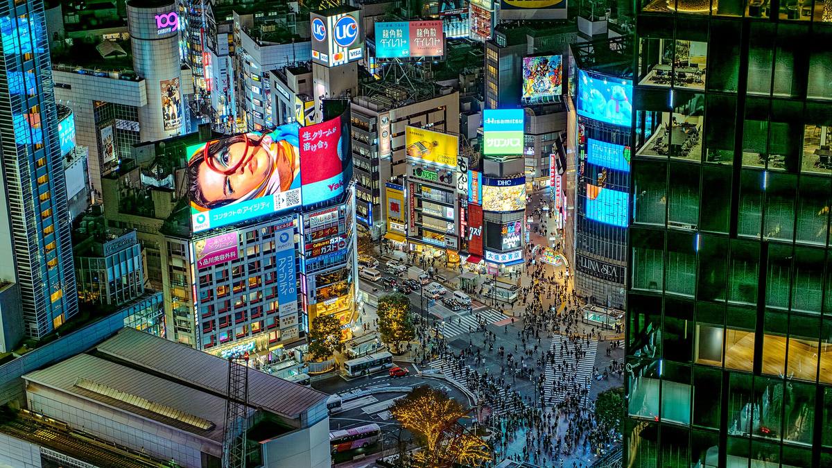 Shibuya-krysset sett ovenfra om kvelden, omgitt av høye bygg med store lysreklamer