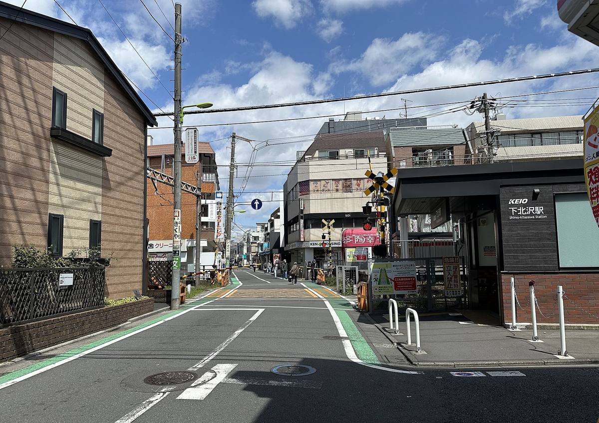 Smal gate med planovergang og små butikker utenfor Shimokitazawa stasjon i Tokyo