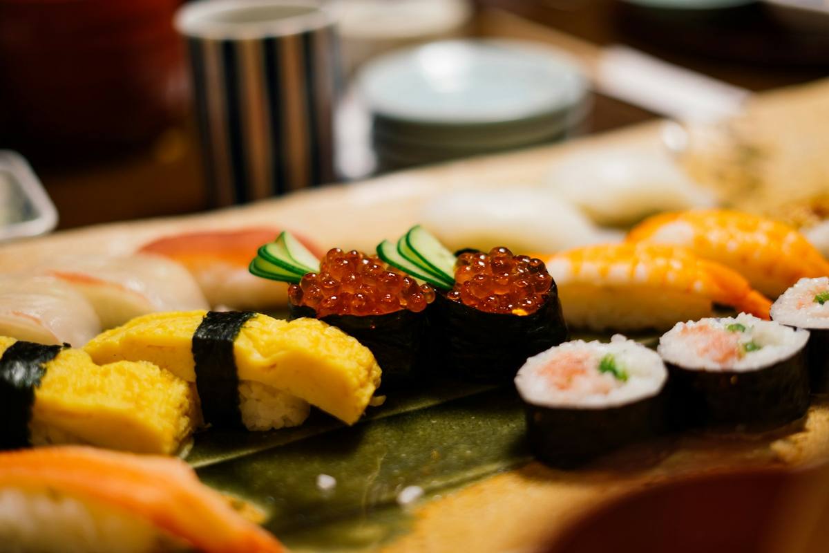 Nigiri på fat med lakserogn i noribånd, omelettbit, reke og hvitfisk, med små makiruller ved siden