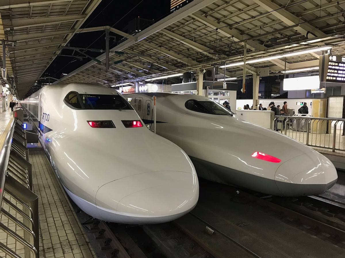 To shinkansen med lange, spisse neser står ved siden av hverandre ved perrongen
