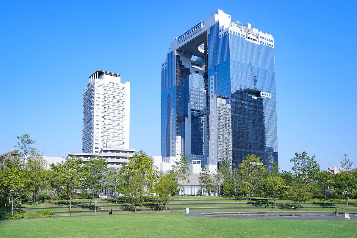 Umeda Sky Building med den åpne takhagen mellom tårnene, sett fra en grønn park i Osaka