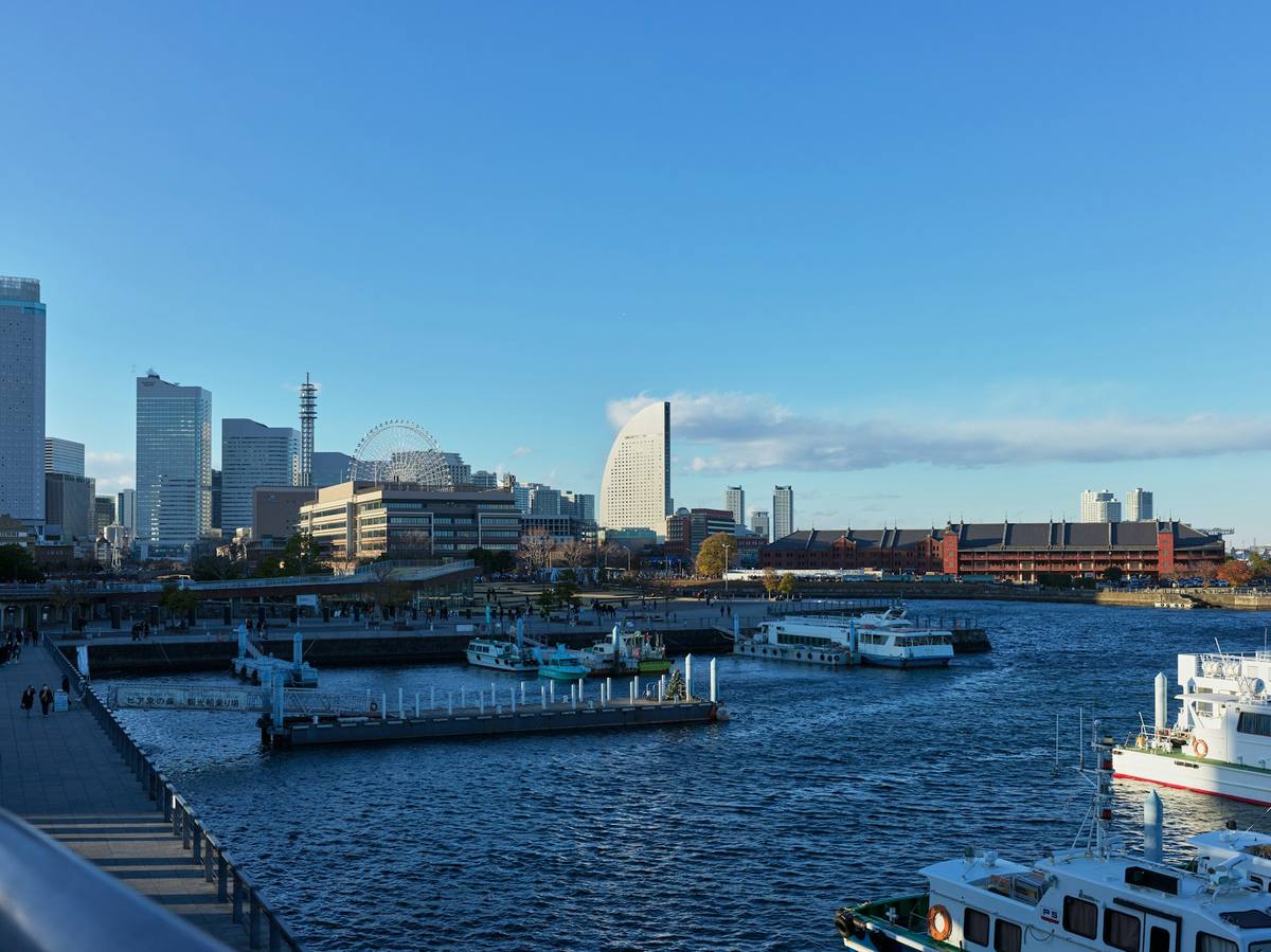 Havnefronten i Yokohama i dagslys med høyhusene i Minato Mirai, et pariserhjul og de røde murlagerbygningene, og båter fortøyd i forgrunnen
